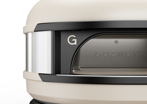 Close-up of cream-colored Gozney Bone Pizza Dome Oven entrance with stainless steel trim for outdoor grilling use.