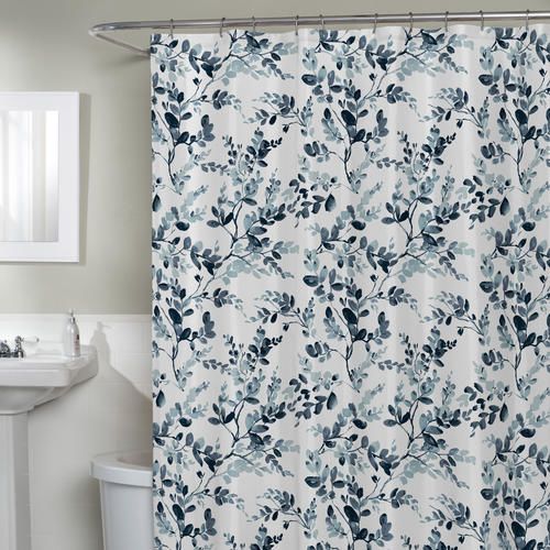 Blue and gray watercolor botanical patterned shower curtain hanging in a bathroom setting with white fixtures.
