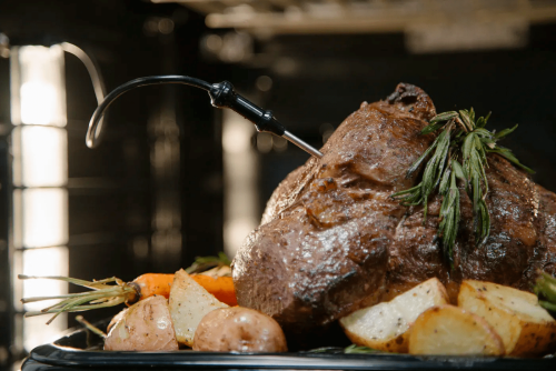 Roast seasoned with fresh herbs and vegetables cooking inside professional double wall oven from Thermador collection