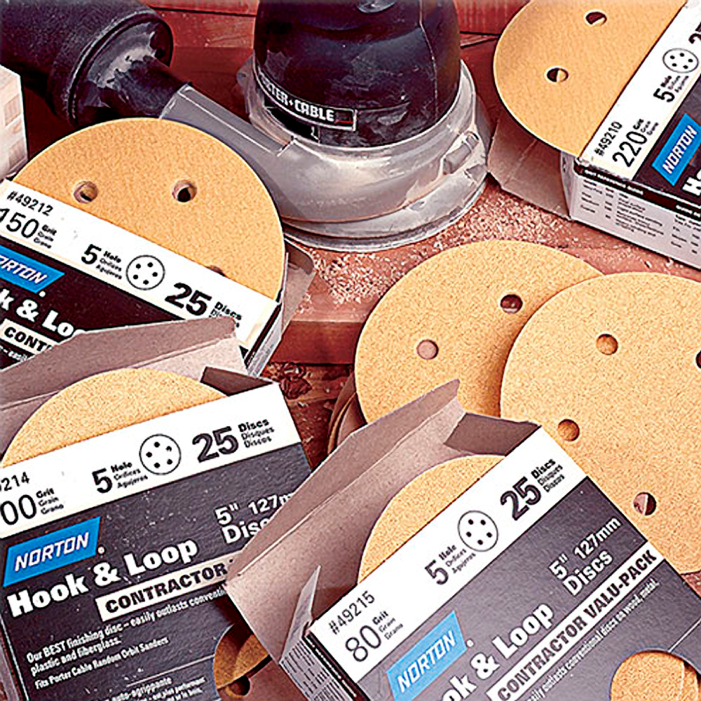 Assorted Norton hook and loop sanding discs displayed with handheld sander for tools and home improvement projects