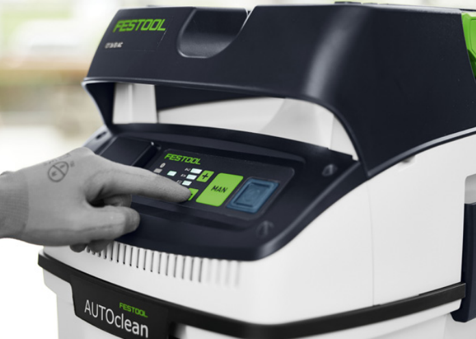 Hand pressing control panel button on Festool CLEANTEC dust extractor for woodworking use