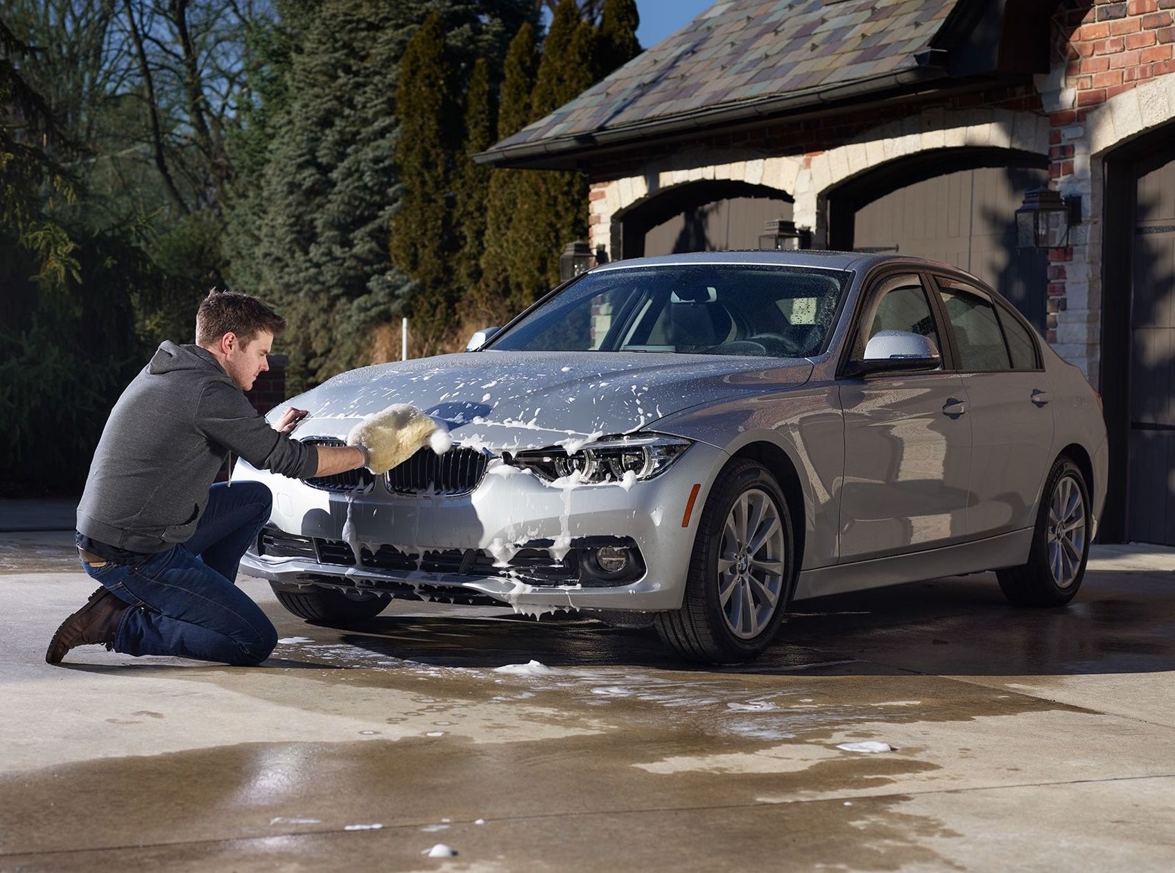 Man using a microfiber wash mitt to clean a silver sedan in automotive tools and accessories collection under $50