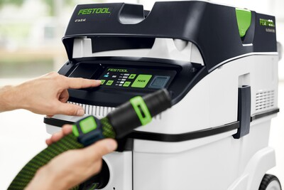 Hand interacting with control panel of Festool dust extractor in woodworking tools and air filtration collection