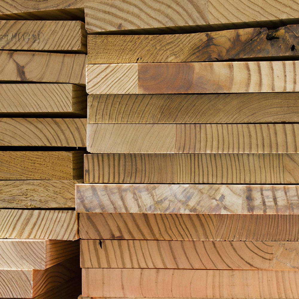 Stack of various light and medium-toned wooden boards showing natural grain patterns and smooth cut edges, arranged in a neat pile.