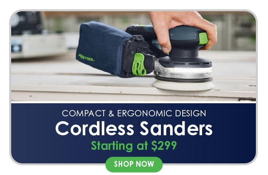 Hand holding a compact cordless orbital sander with a dust collection bag smoothing a wooden surface in a home improvement setting.