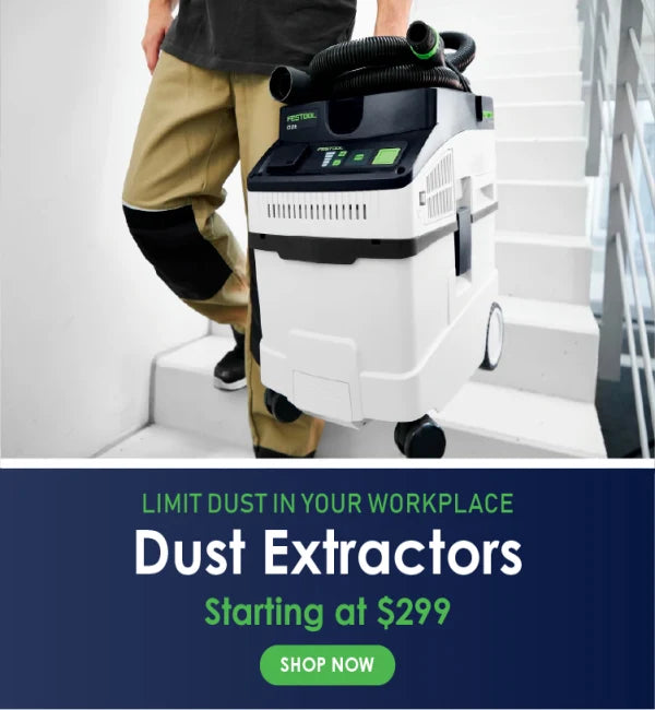 Person carrying a compact dust extractor with black and white casing and green accents on a stairway, promoting cleaner work environments.