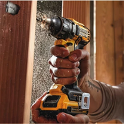 Close-up of a person’s hand operating a cordless drill to bore into wooden framing, with wood dust flying during the Home Improvement task.