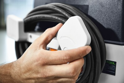 Hand securing coiled power cord on Festool dust extractor in woodworking tools and air filtration collection