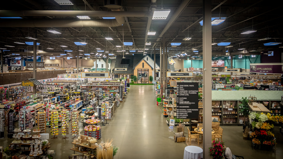 Wide interior view of a large home improvement store featuring aisles filled with various tools, hardware, home goods, and a central display resembling a small house.