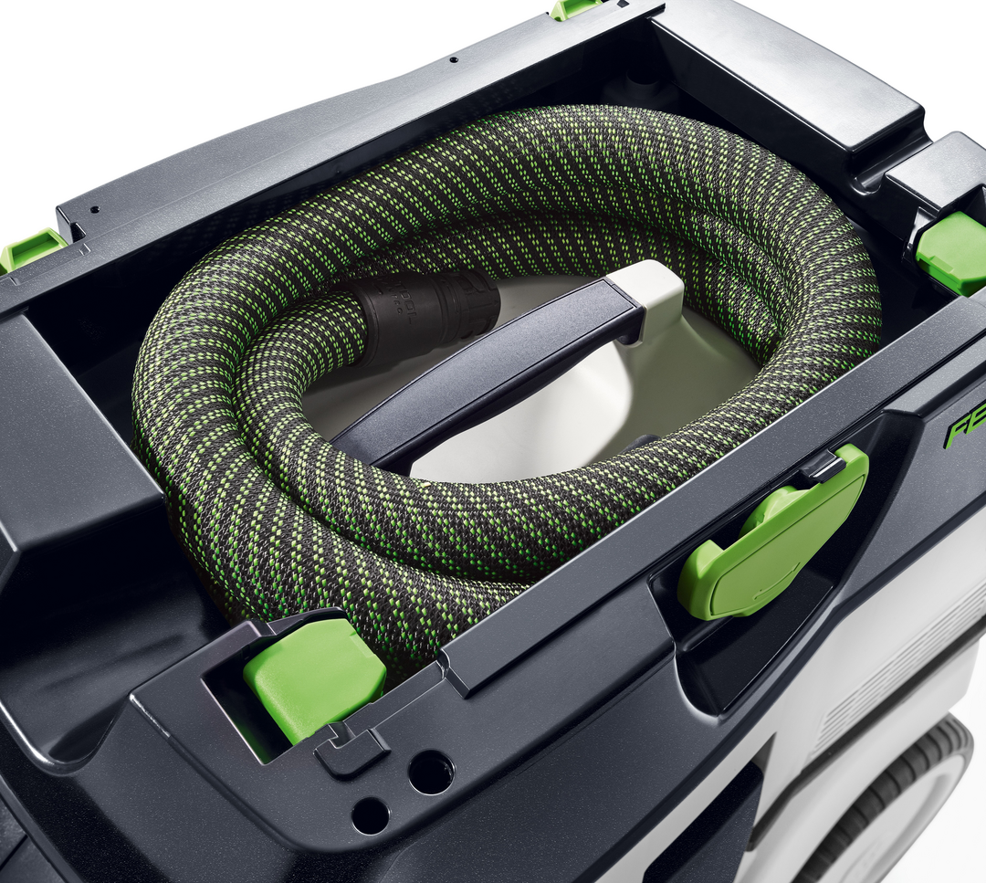 Coiled black and green flexible hose stored inside Festool HEPA dust extractor for woodworking and air filtration tools use