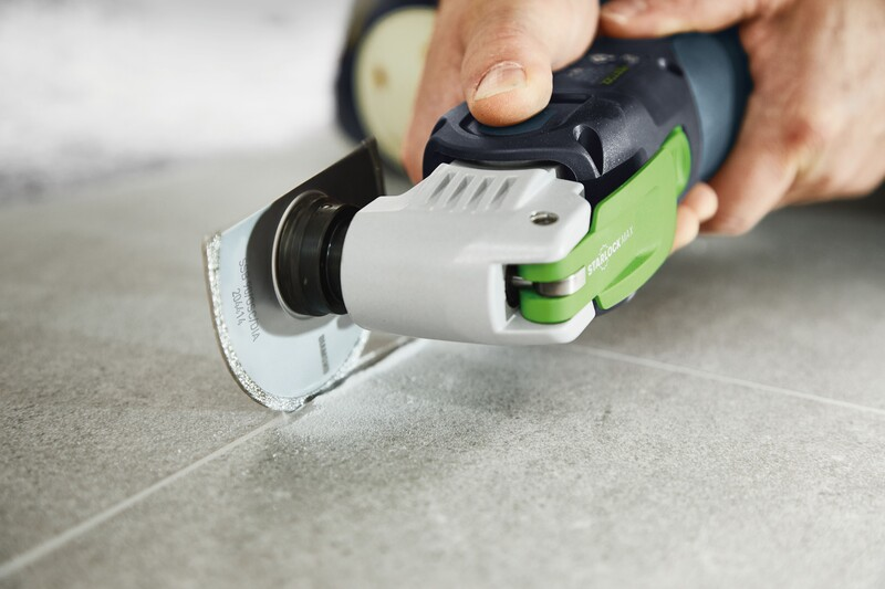 Close-up of a hand operating a precision oscillating tool with diamond saw blade cutting tile grout for home improvement.