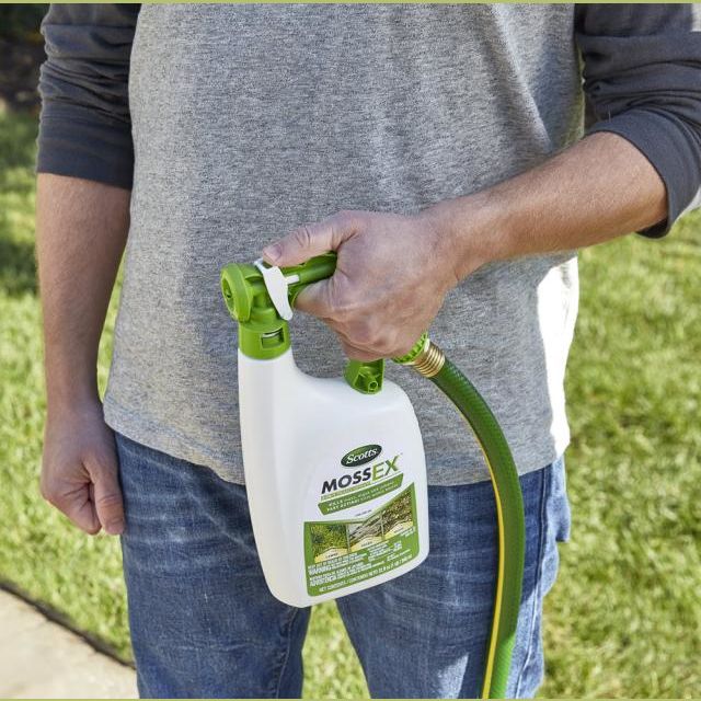 Person holding Scotts MossEX 3-in-1 spray attached to garden hose for lawn care and outdoor home improvement use