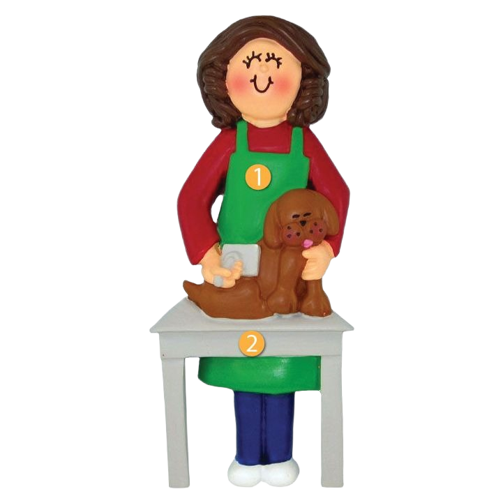 Brown-haired female dog groomer figurine with green apron brushing a brown dog on a white table ornament