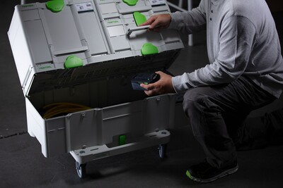Person organizing large white and green Festool Systainer storage box with tool and accessory compartments on workshop floor