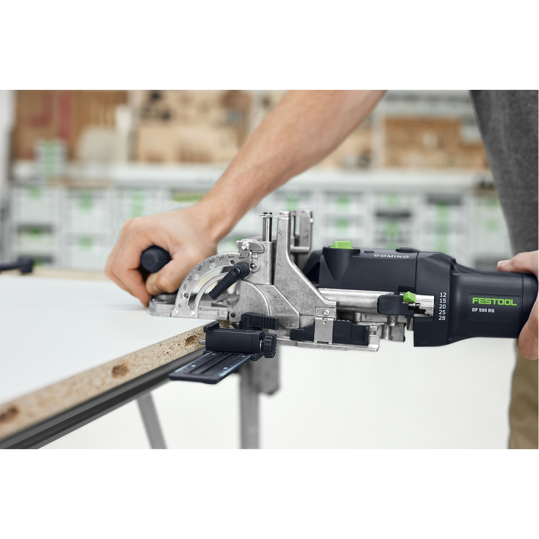 Worker using a Festool 578544 DOMINO joiner to make precise angled cuts on a wood board in a woodworking shop with Power Tools and Woodworking Tools collections.