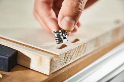 Hand positioning metal Festool corner connector into wood panel mortises for woodworking tools and home improvement projects