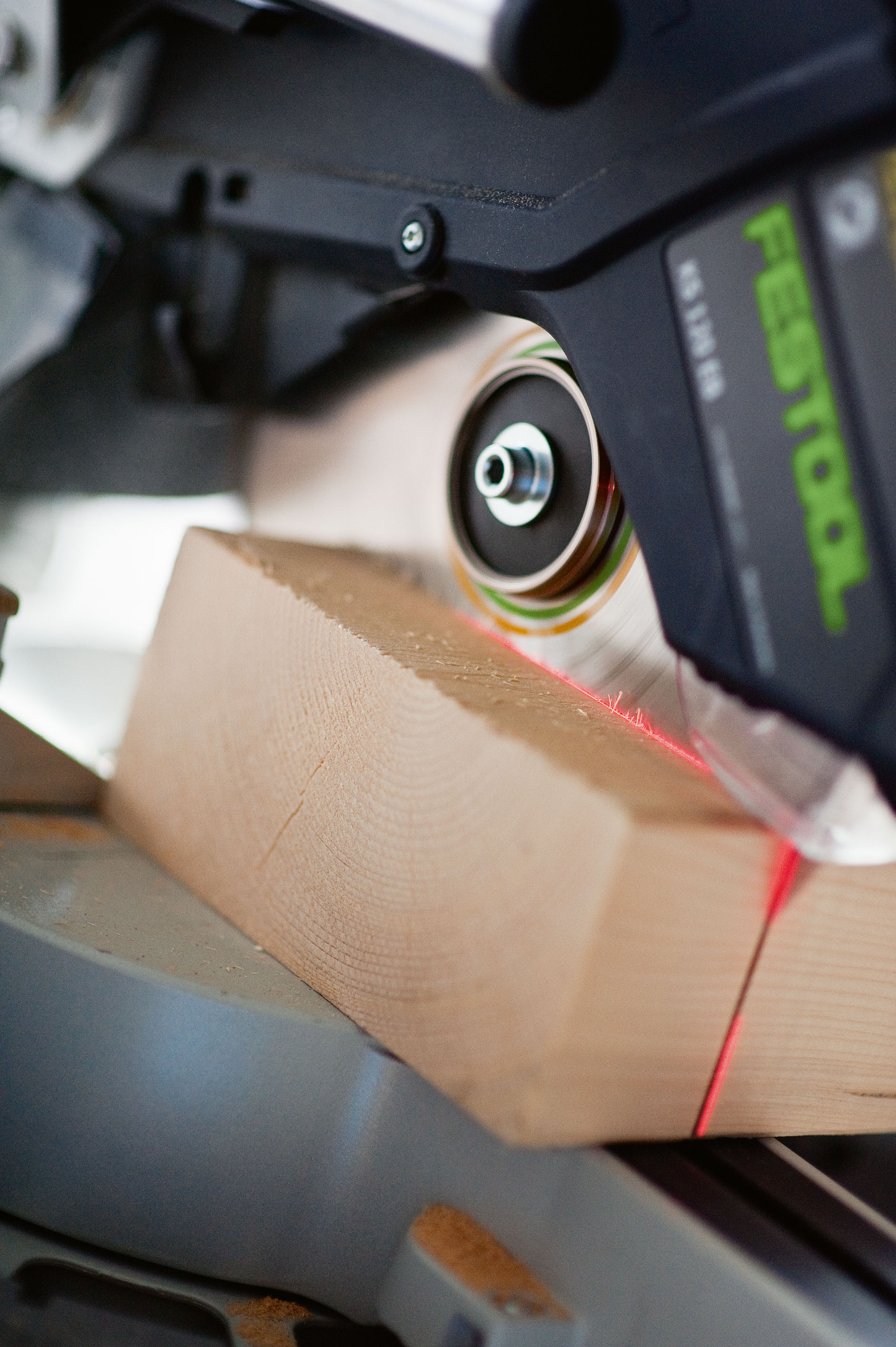 Close-up of Festool sliding compound miter saw cutting wood with red laser guide in power tools and saws collection
