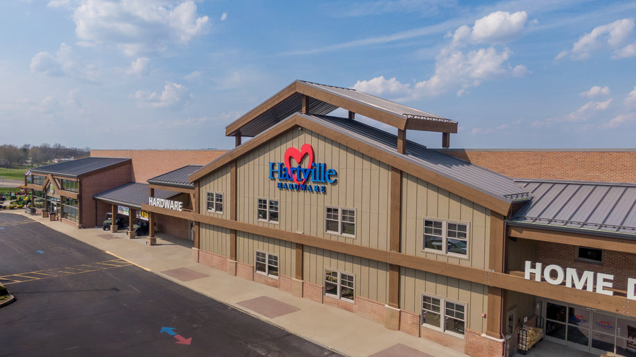 Exterior view of a large retail building with a brown roof and beige siding under a partly cloudy sky during daytime.