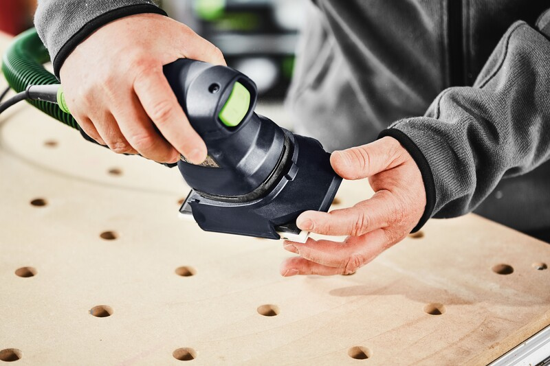 Hands attaching a black Festool sander protector to a power tool over a perforated wooden board for home improvement tasks