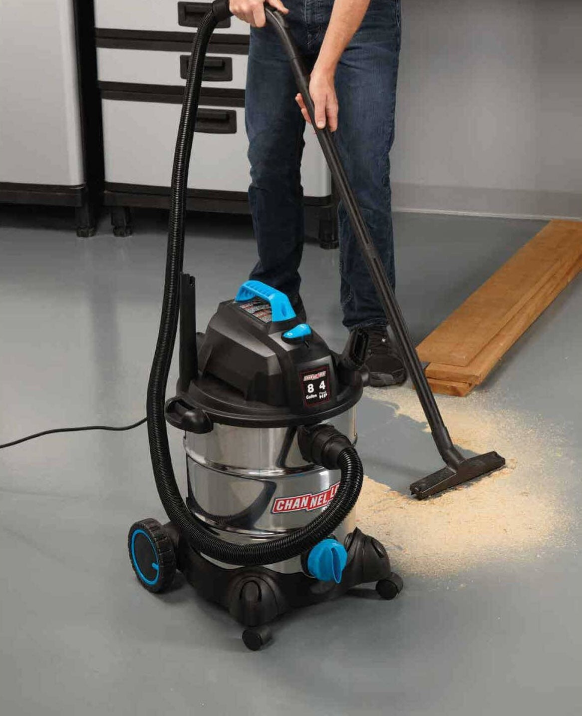 Stainless steel wet/dry vacuum with 8-gallon capacity cleaning sawdust on a workshop floor for home improvement