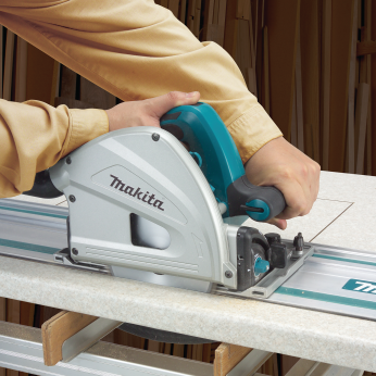 Teal and silver Makita plunge saw cutting a panel using a 55-inch guide rail for precise home improvement work