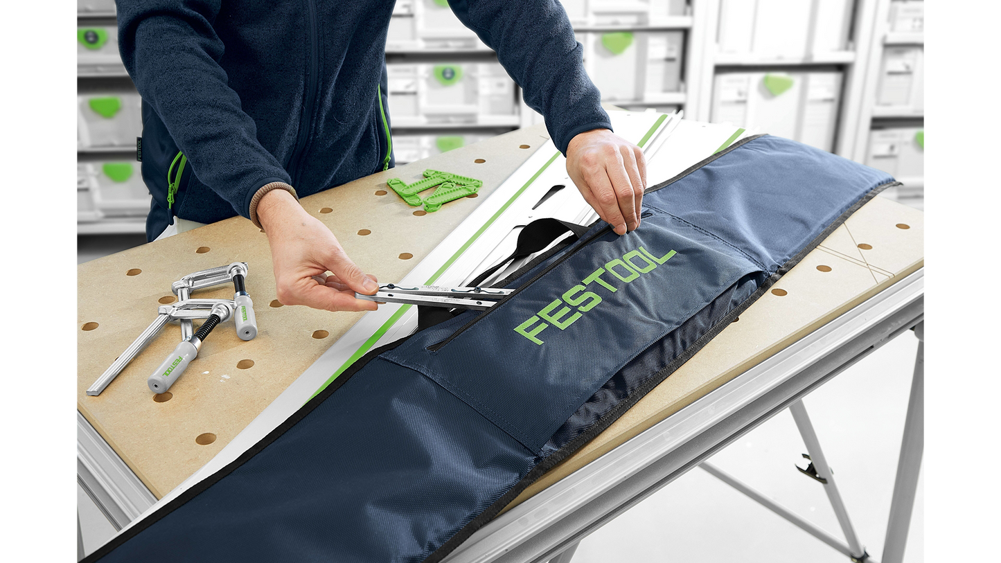 Person adjusting metal guide rail system stored inside protective Festool branded black carrying case in woodworking tool accessory setup