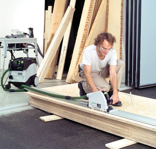 Man wearing safety glasses using Festool plungecut saw with guide rail to cut plywood in power tools and home improvement collections