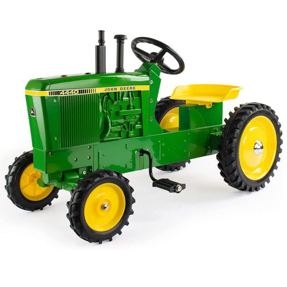 Green and yellow pedal tractor with black steering wheel and large rear rubber tires for children’s outdoor play