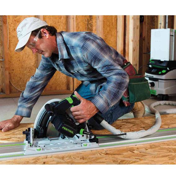 Man wearing safety glasses using a plungecut saw with guide rail for precise cutting on a wood surface in power tools collection