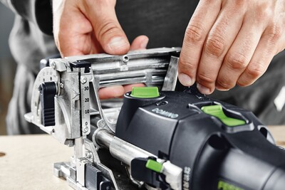 Hands setting depth adjustment on a Festool Domino joiner tool for precise cuts in woodworking power tools collection