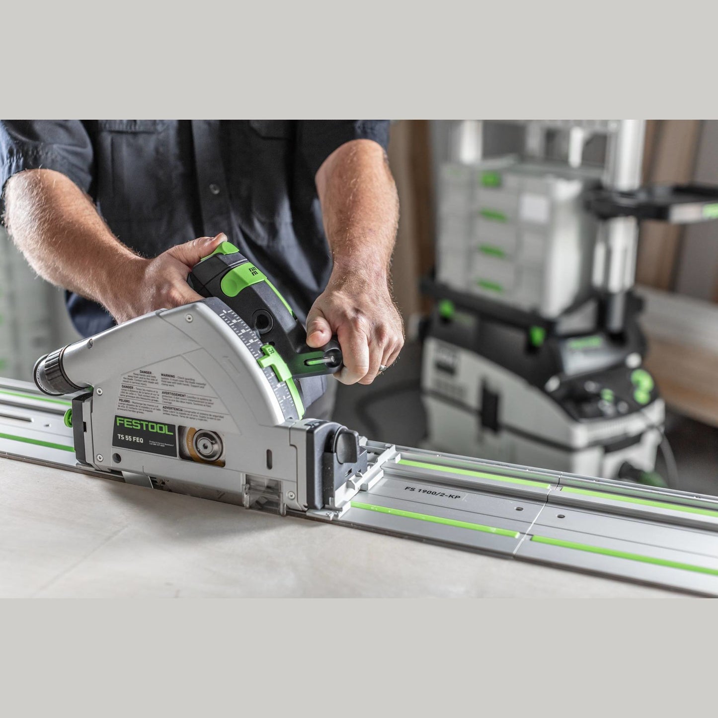 Person using a Festool plunge-cut track saw with 55-inch guide rail for precise woodworking cuts in a workshop setting