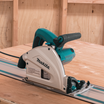 Teal and silver Makita plunge saw positioned on a guide rail cutting smooth plywood for home improvement tasks