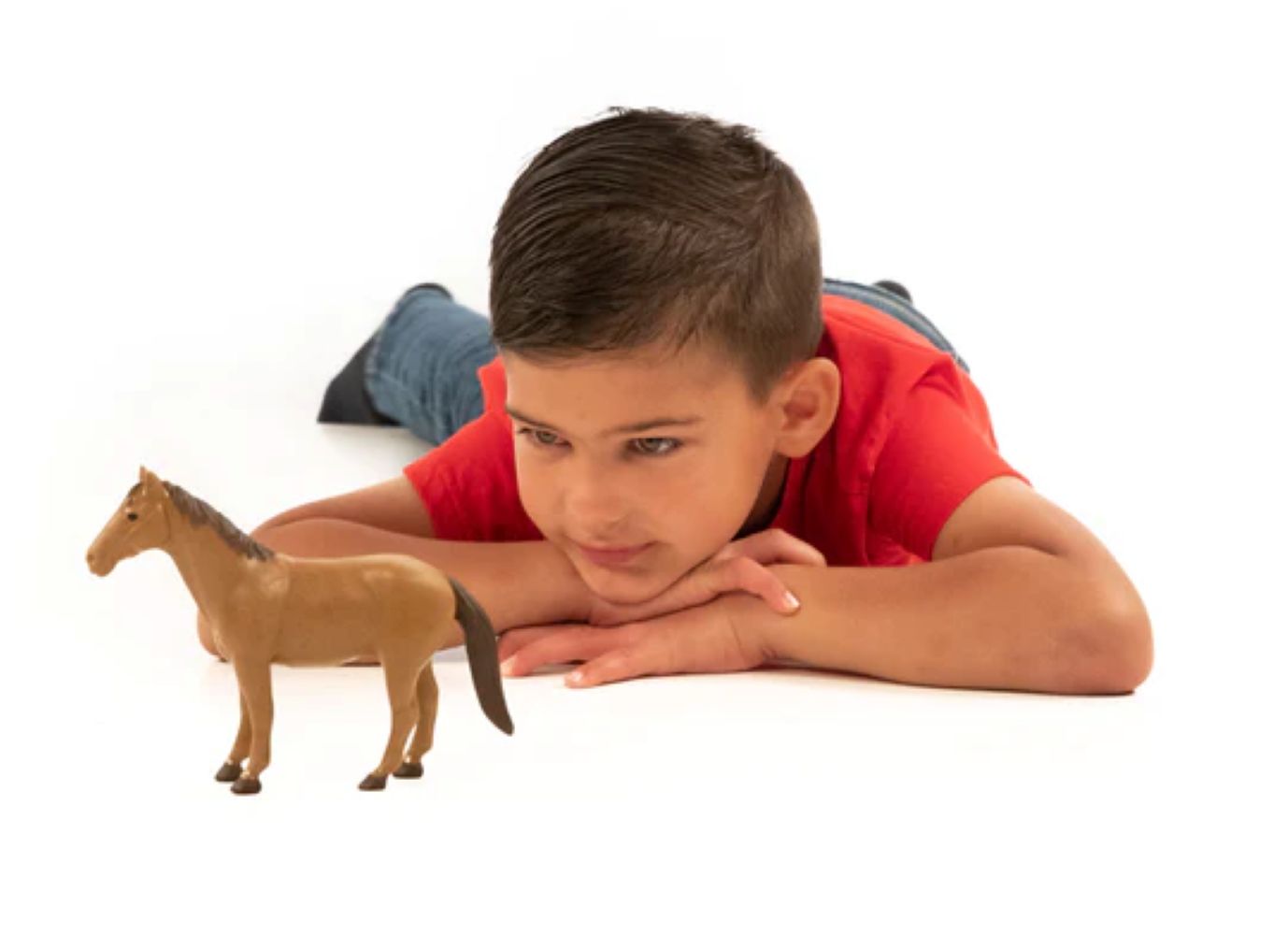 Child lying on floor looking at a brown plastic toy horse from Bruder Toys in the Toys & Games collection