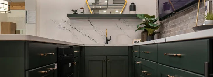 Cozy basement bar area with deep green cabinetry, white marble countertops, a black faucet, floating shelf with decor, and a wall-mounted TV.