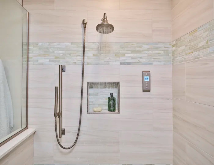 Contemporary shower area with light beige tile walls, a mosaic tile accent strip, a built-in niche holding bath items, and a stainless steel rainfall showerhead with handheld attachment.