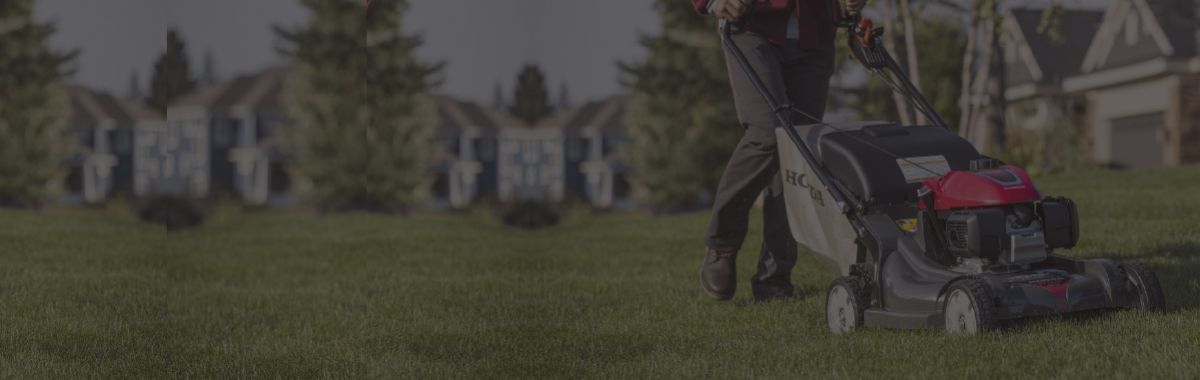 Person mowing a well-maintained green lawn in a suburban neighborhood, showcasing outdoor yard care and lawn maintenance.