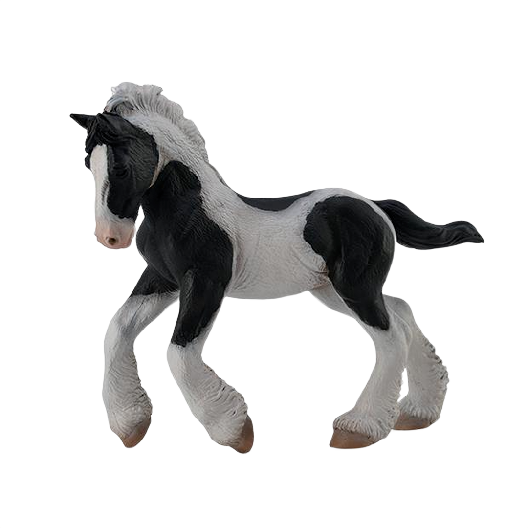 Black and white piebald gypsy foal figurine with detailed mane and feathered legs in a playful pose