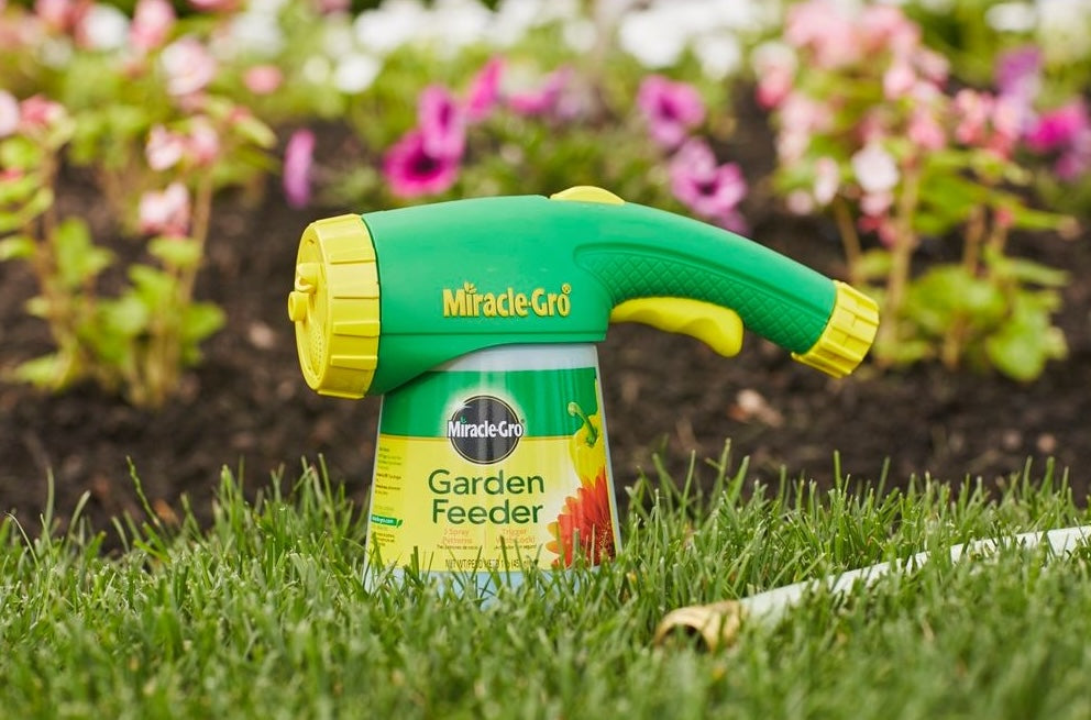 Green and yellow garden feeder with trigger-lock for one-handed application of plant food in lawn care and plant care