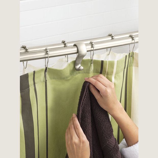 Hands adjusting striped green shower curtain on brushed nickel double curved shower rod in bathroom setting