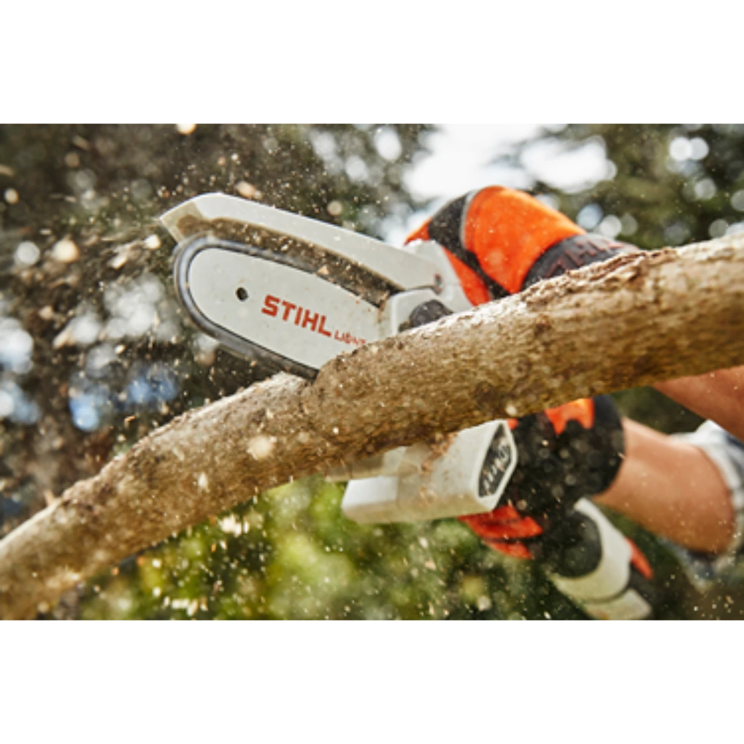 Handheld battery-powered garden pruner cutting a tree branch with wood chips flying in an outdoor setting