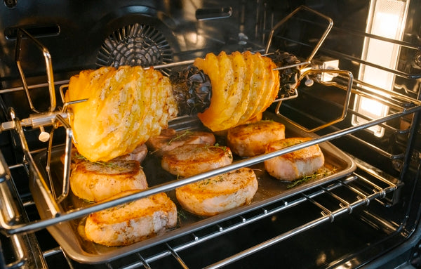 Convection rotisserie cooking pork medallions and spiral-cut pineapple inside stainless steel double wall oven from Thermador collection