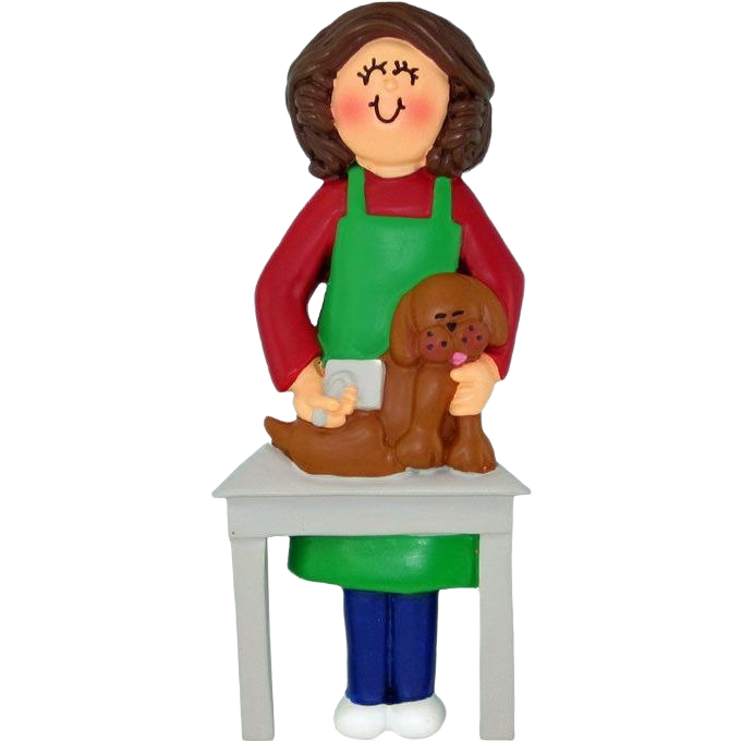 Brunette female dog groomer figurine in green apron brushing brown dog on white table holiday ornament