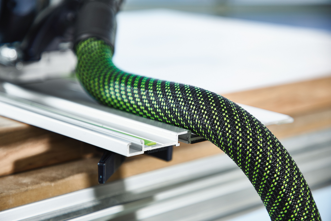 Flexible green and black dust extraction hose attached to guide rail for woodworking dust collectors and tools