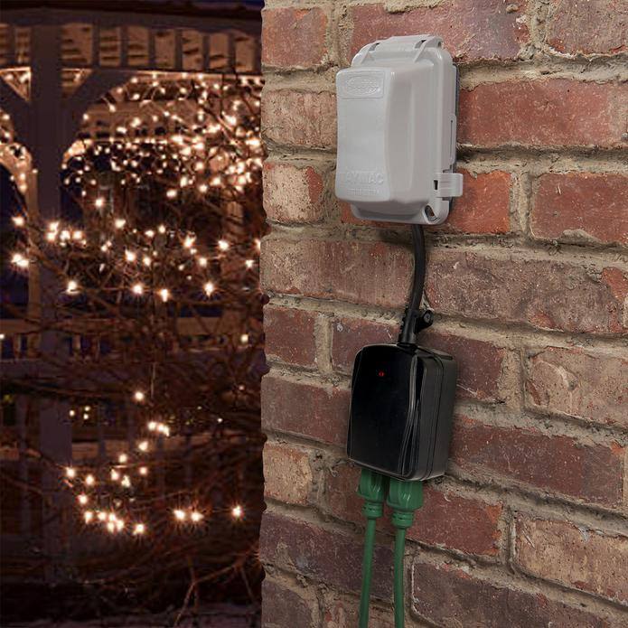 Outdoor wireless remote control and transmitter mounted on brick wall with connected green extension cords for tools use