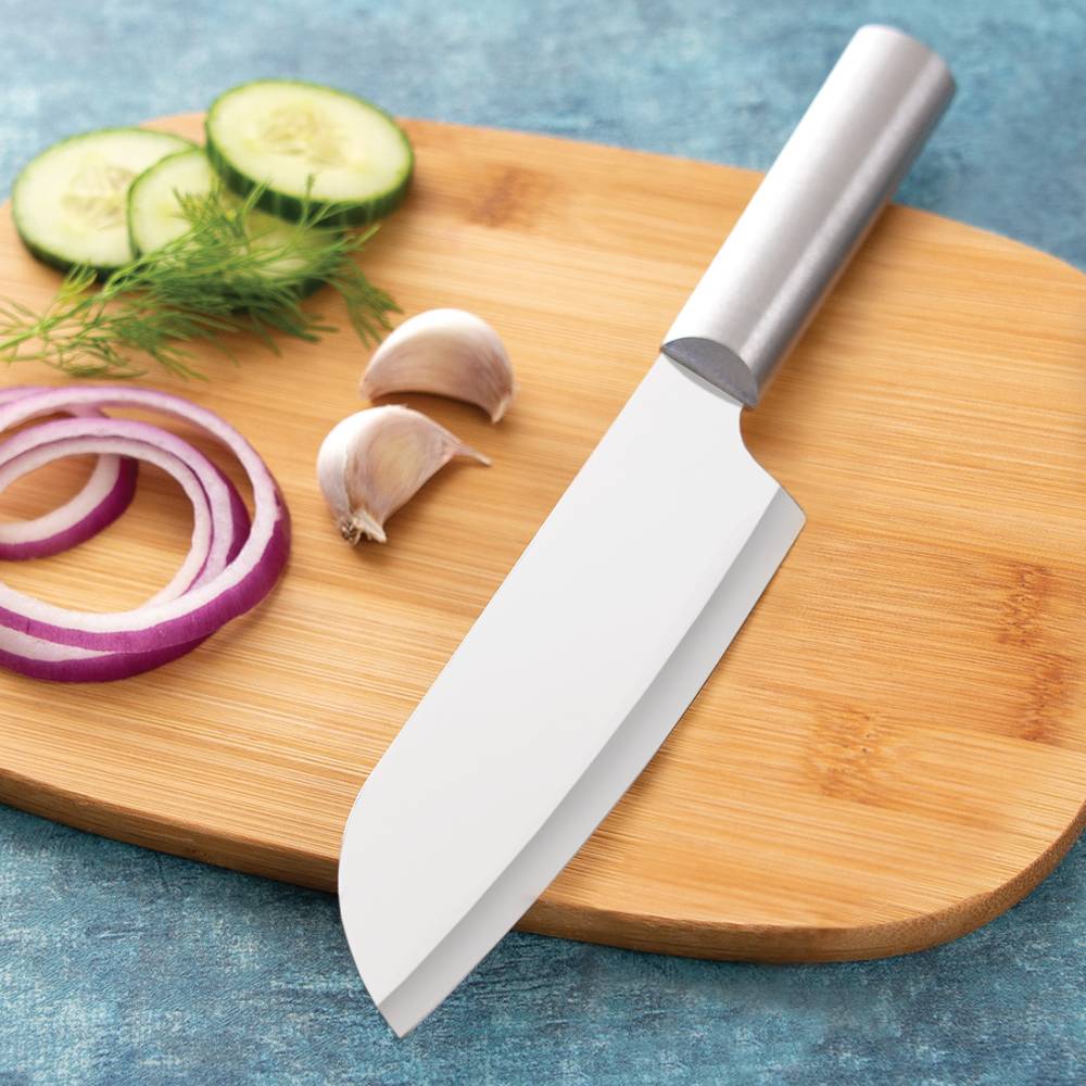 Stainless steel cooks knife with smooth metal handle resting on wooden cutting board with garlic, cucumber, and onion slices