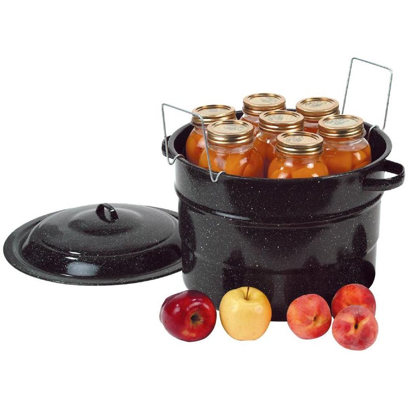 Black speckled preserving canner with lid, filled with jars of preserved fruit and fresh apples nearby for home use