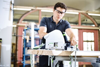 Worker wearing safety glasses using Festool plungecut saw with guide rail for precise woodworking in power tools collection