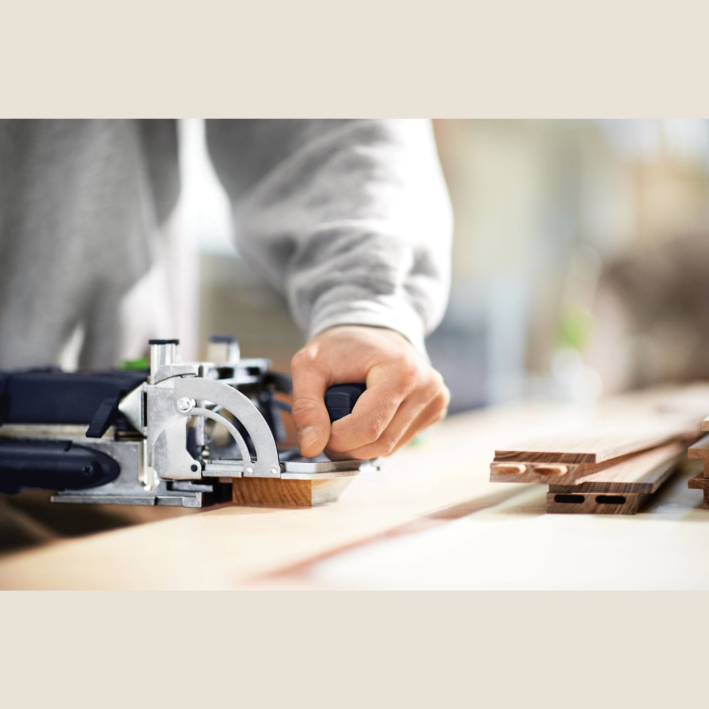 Close-up of woodworking joinery with Festool Domino power tool creating precise mortise cuts on wooden boards in workshop environment