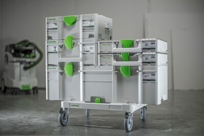 Stacked gray and green interlocking Festool tool storage boxes on wheeled cart for workshop and jobsite organization