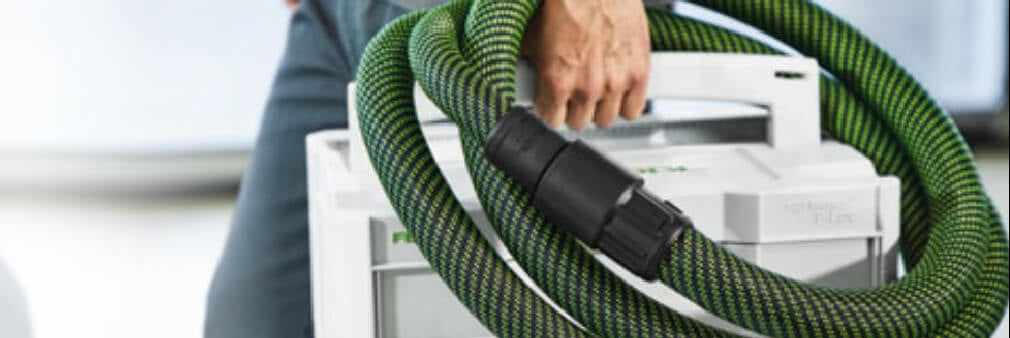 Person carrying a white storage box wrapped with a green and black flexible hose, suggesting organized transport of tools or equipment for home improvement tasks.
